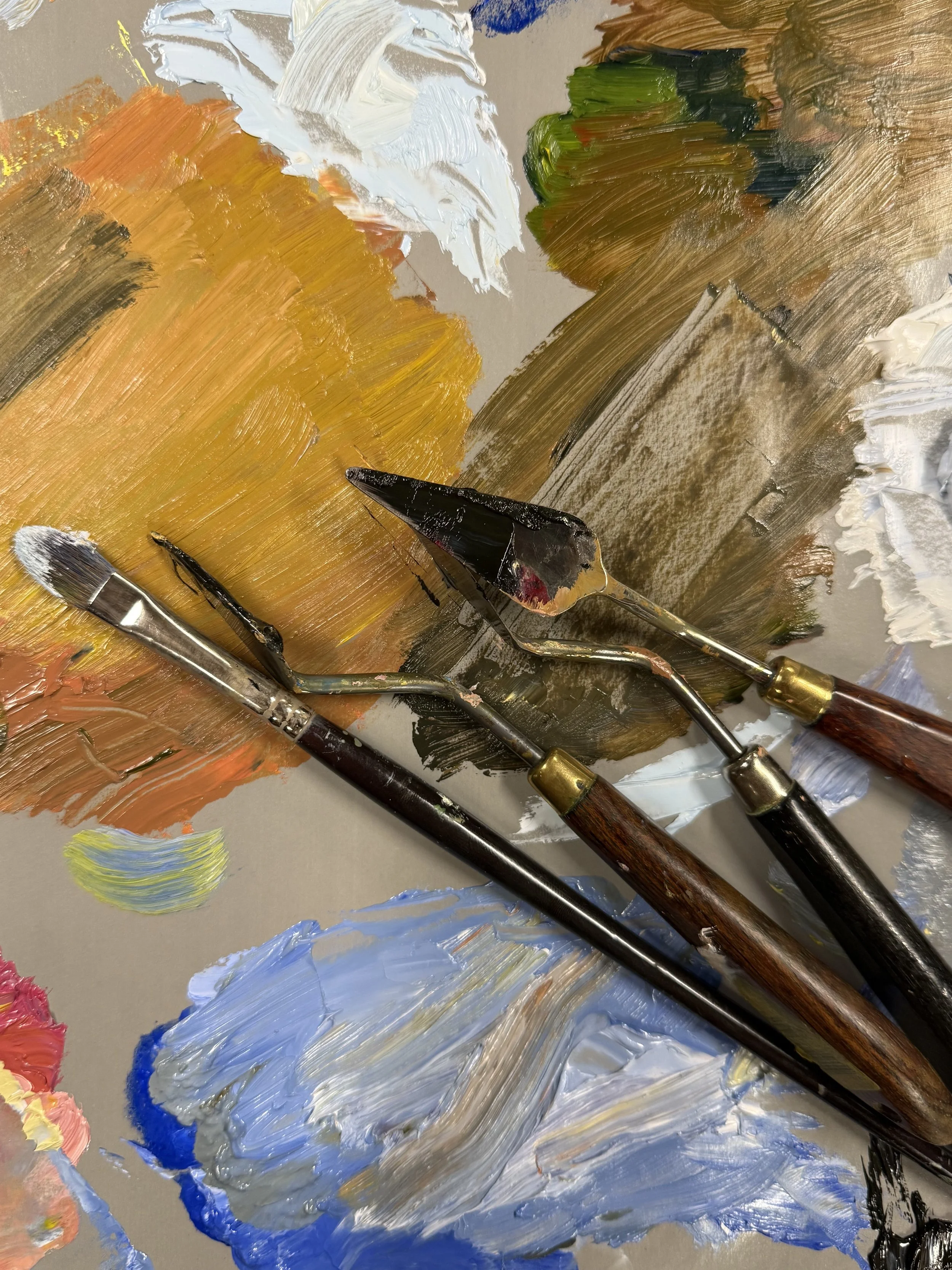 Palette knives resting on rich strokes of paint